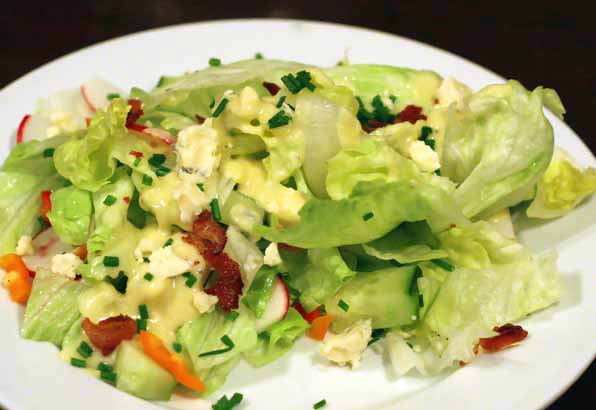 salad with dressing on it sitting on a white plate
