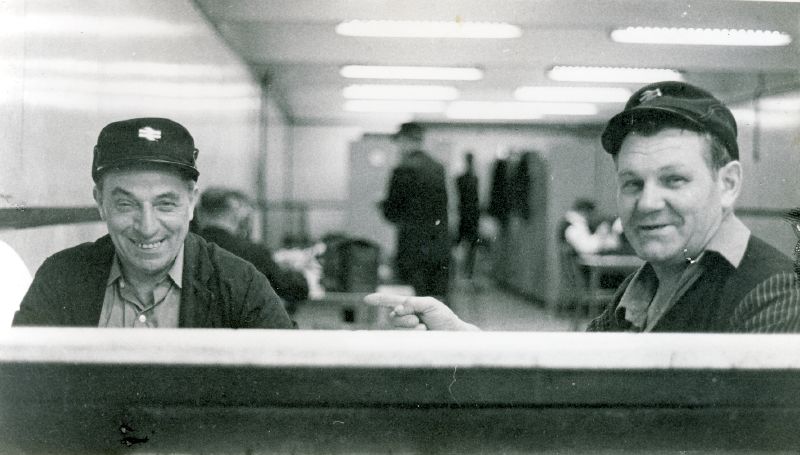 two men sitting on a table smiling at the camera