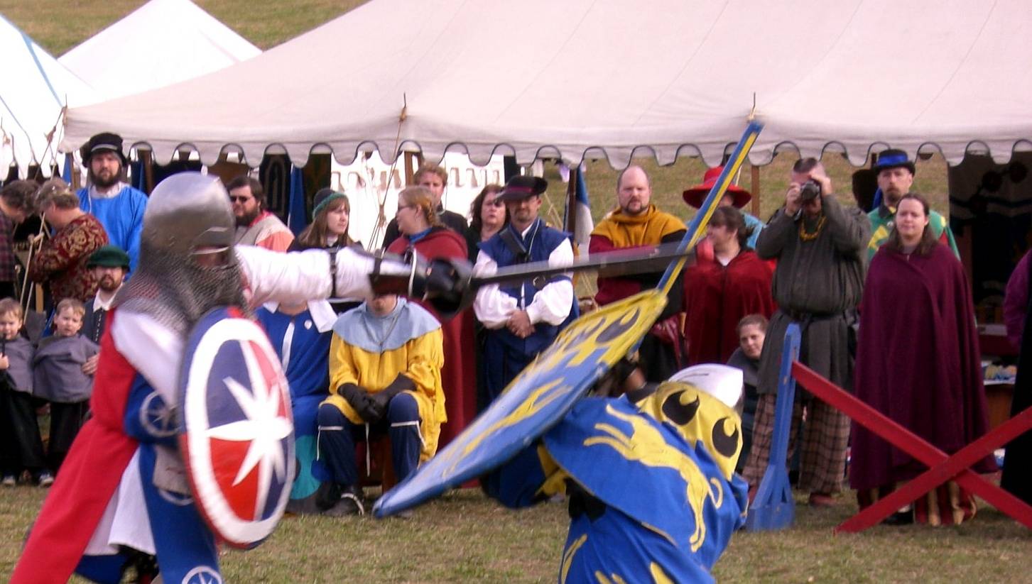two men in medieval armor hold swords as they fight