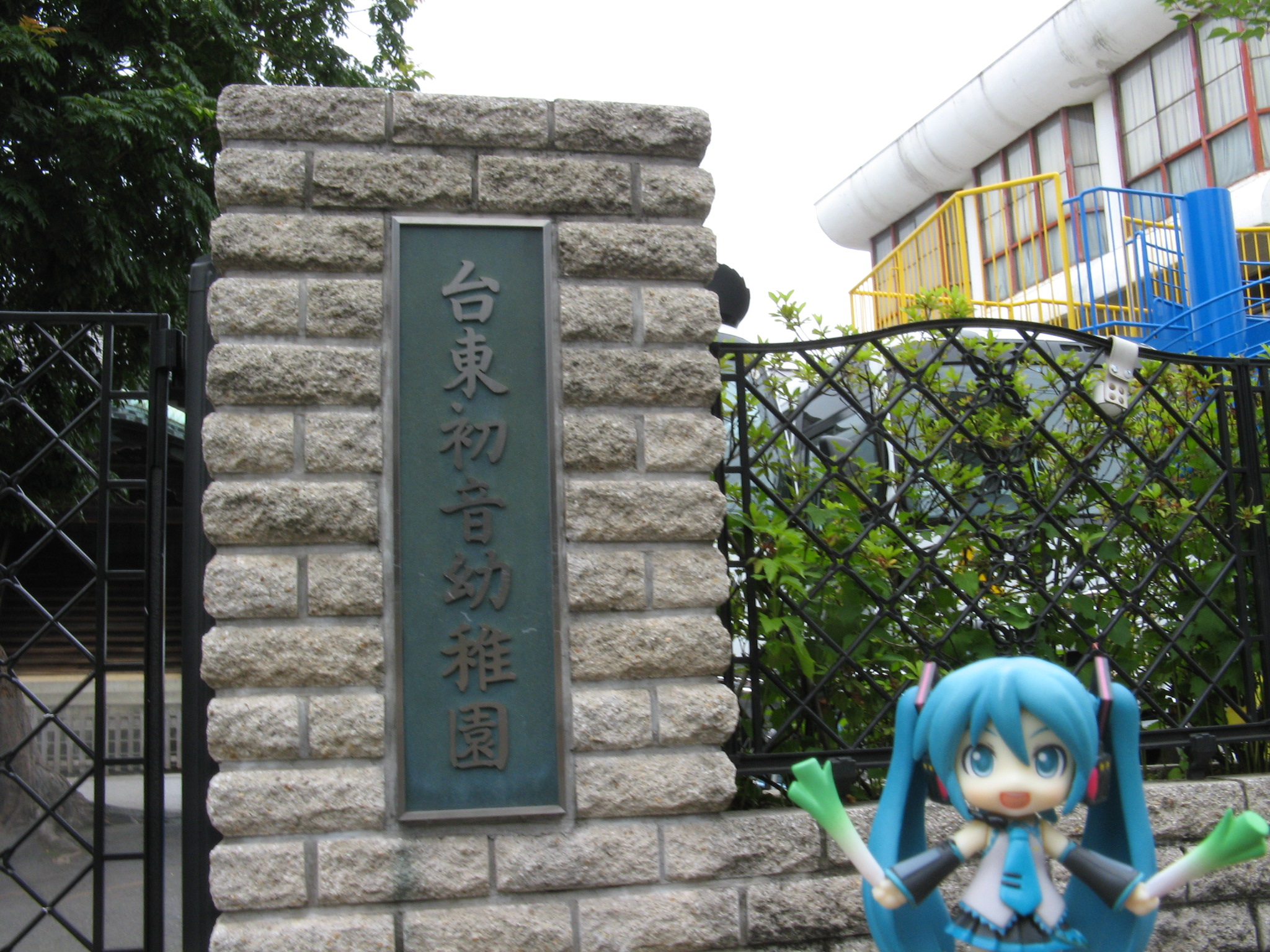 an artificial statue in front of a building with a fence behind it