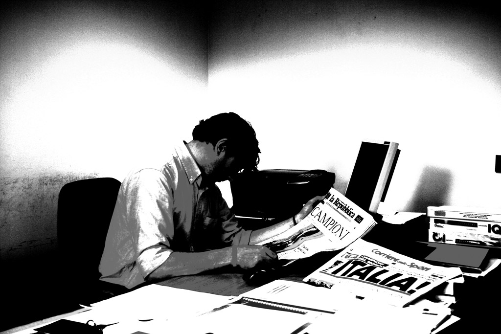 black and white po of man in office reading a paper