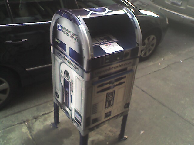 the view of a mailbox on a sidewalk near a car
