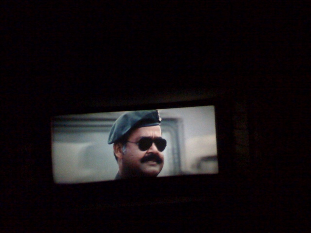 a man in sunglasses and a hat is on a large screen television