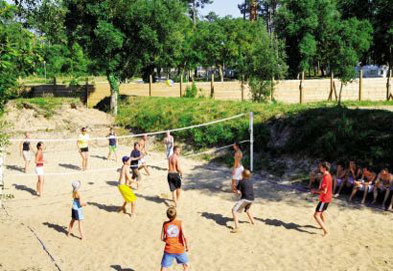 many children playing volleyball on a sandy beach