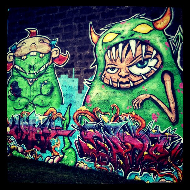 graffiti painted on the side of a building with two cartoonish monsters