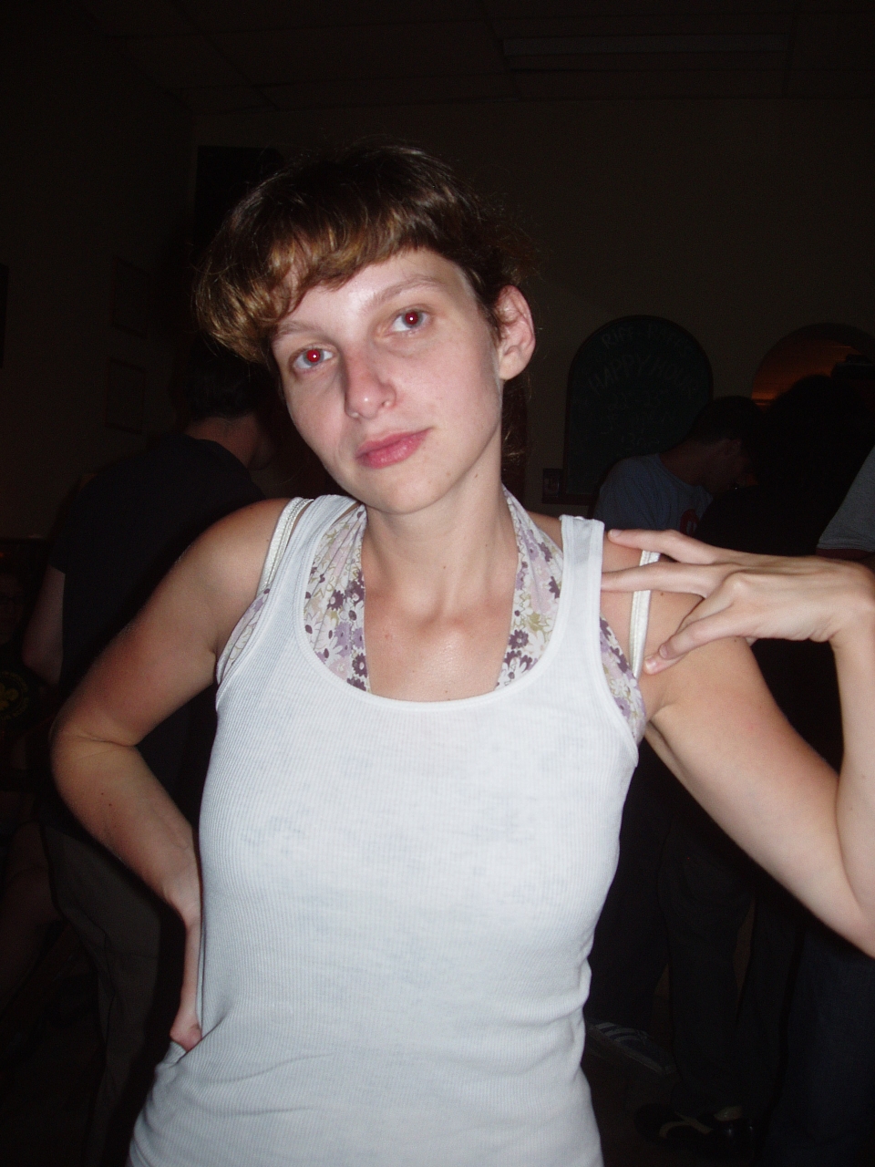 a young lady wearing a white tank top in front of a group