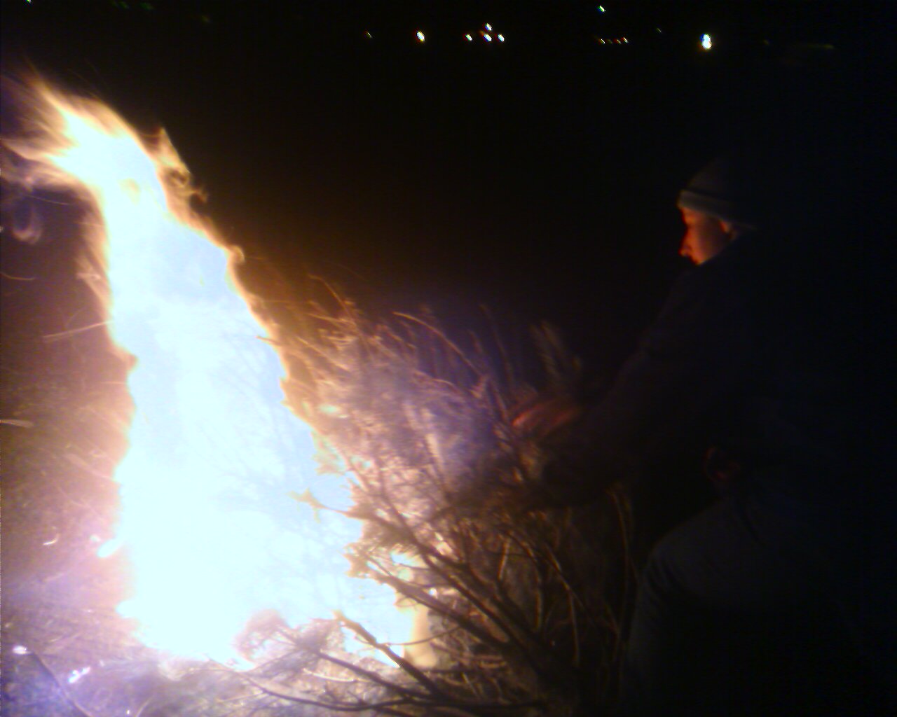 a man standing by some fire with his hands on the back of a flaming