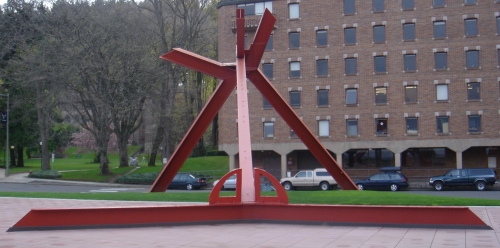 a large red statue is sitting in the middle of a plaza