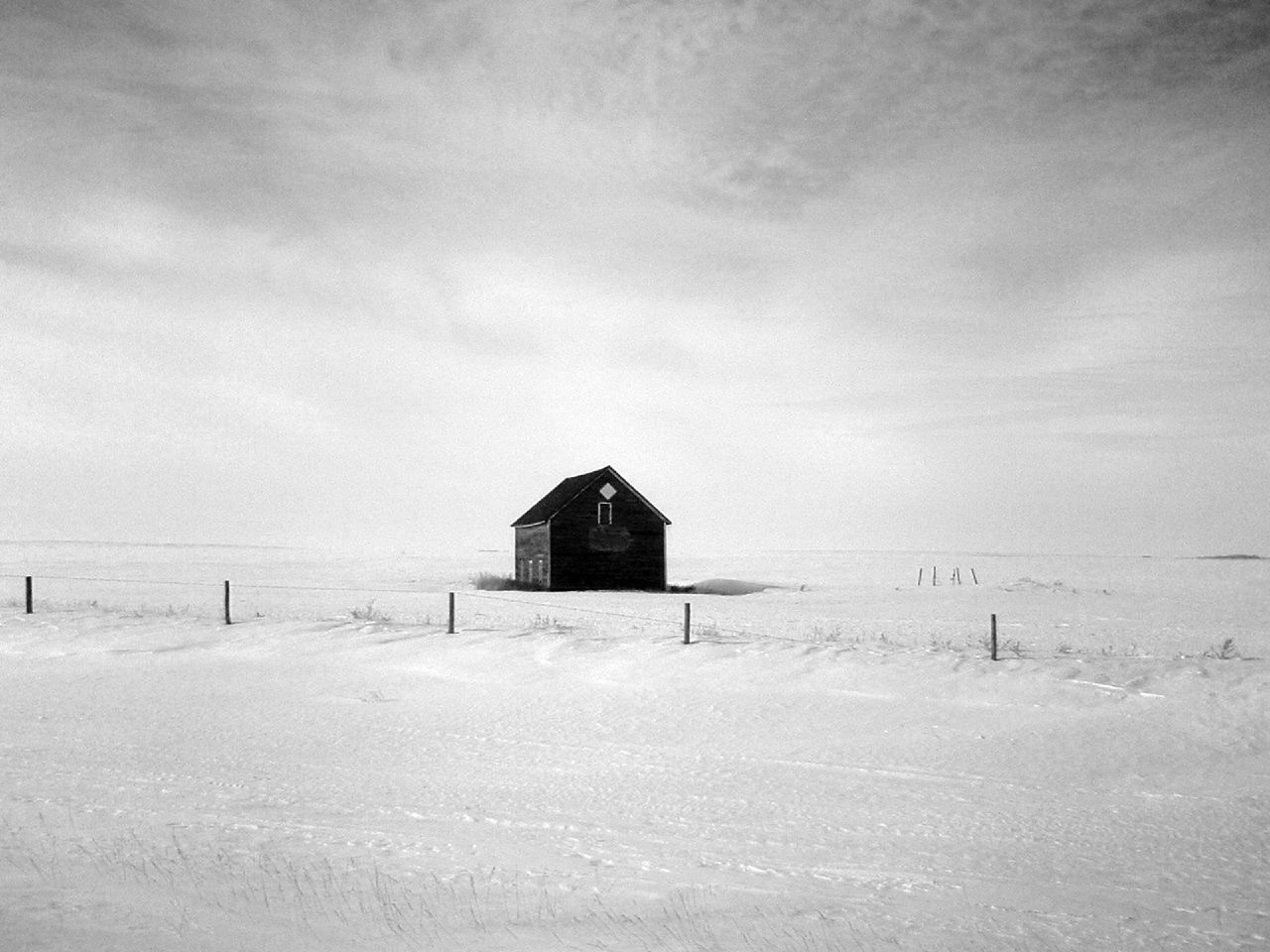 a barn on a snow covered hill in a field