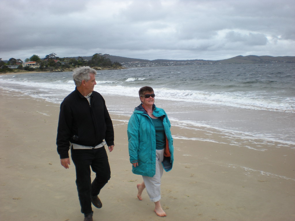 two people walking on the beach while it rains