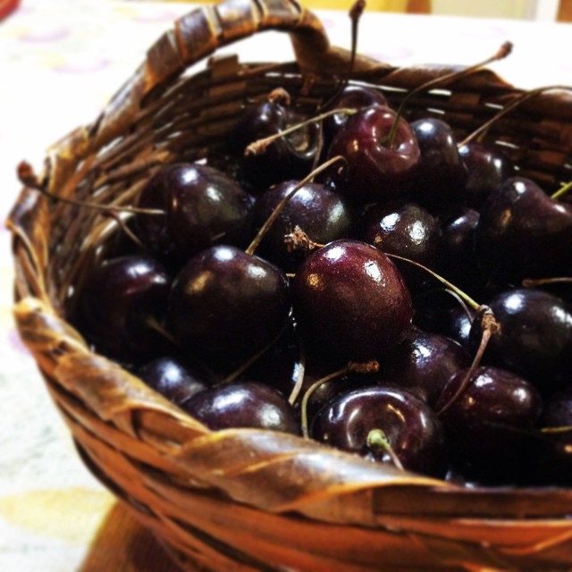 a basket filled with cherries sits on a table