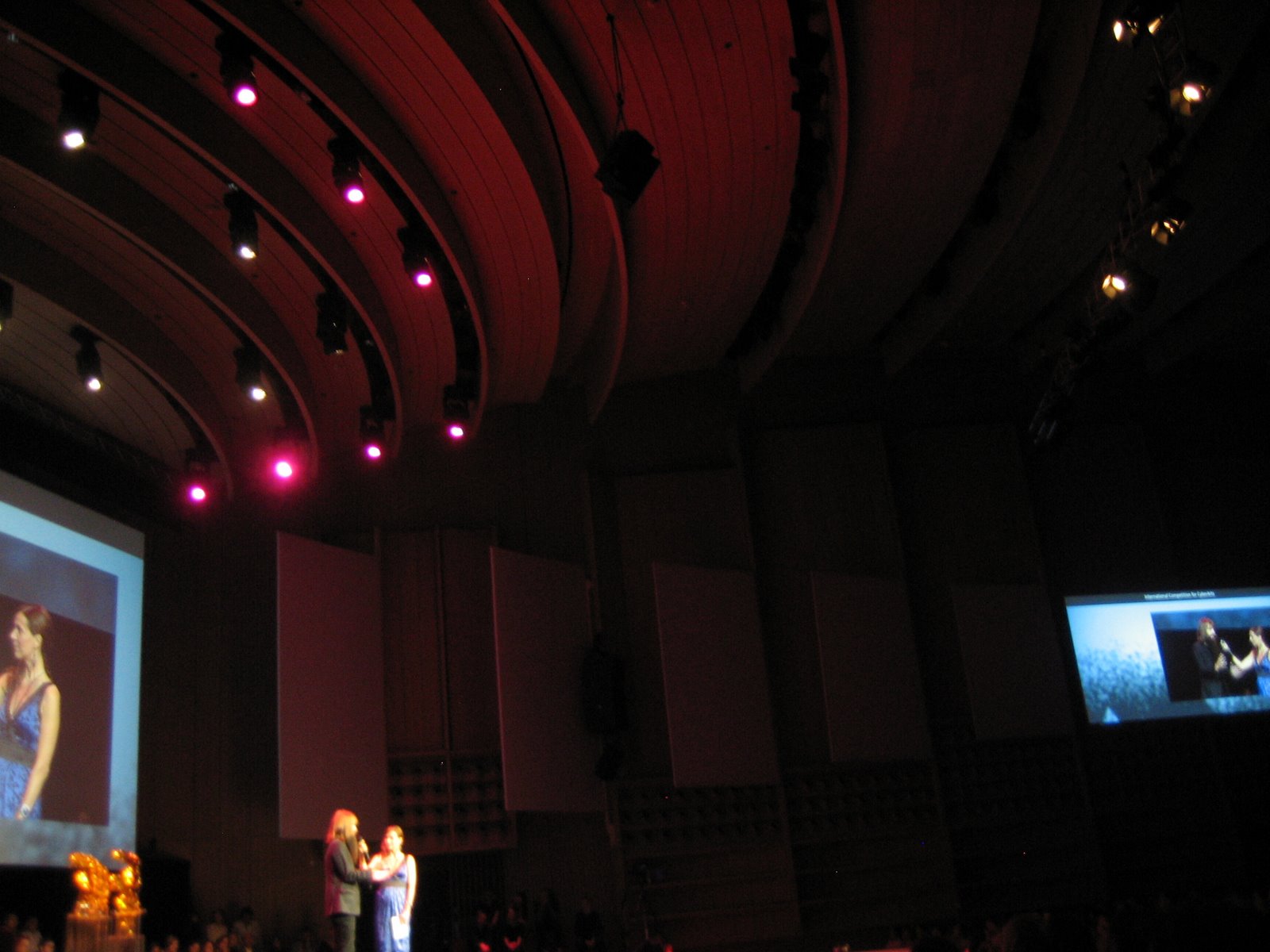 two people standing on stage talking in front of a crowd