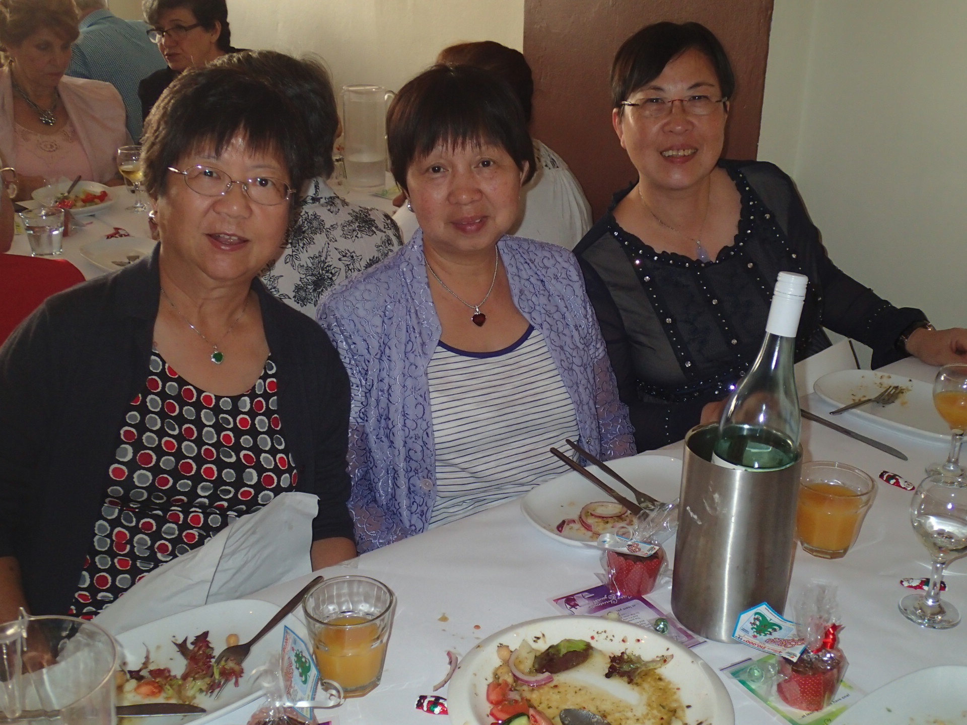 three women sitting at a dining table posing for the camera