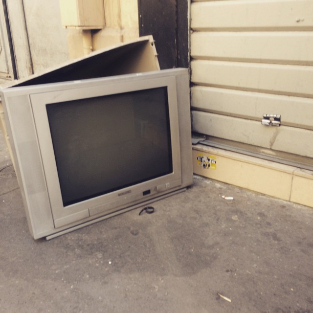 a television and box on the sidewalk next to some buildings