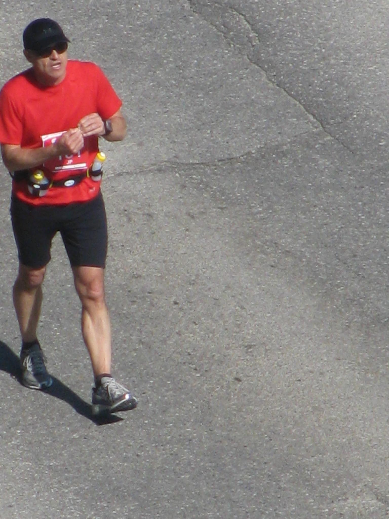 a man in shorts and a red shirt running with a skateboard