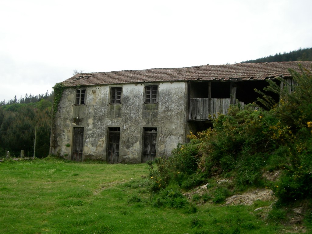 an old run down house sitting in a field