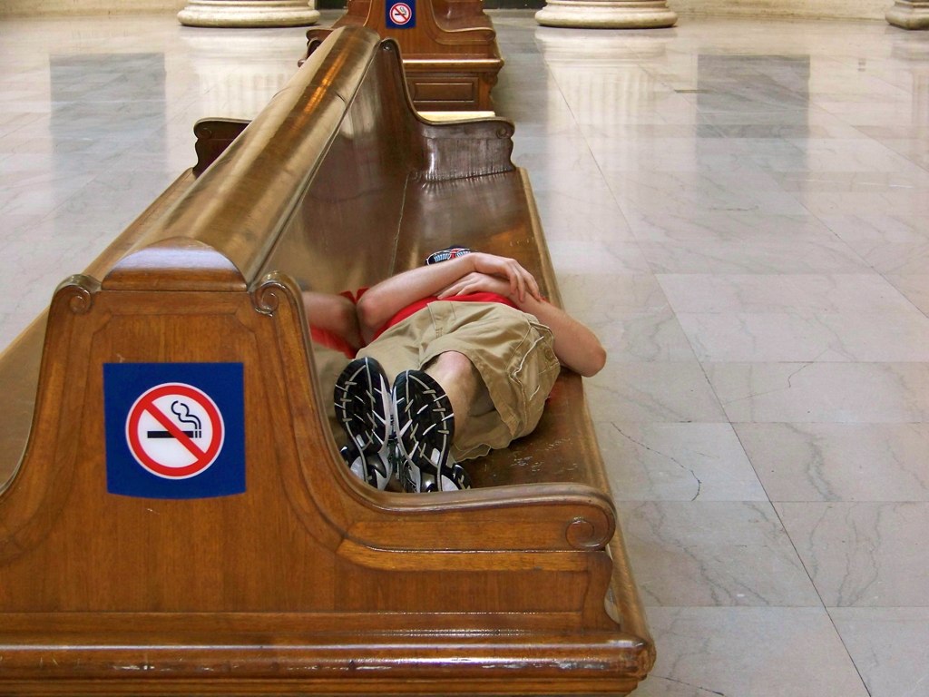 a little boy sitting on a bench sleeping in a mall