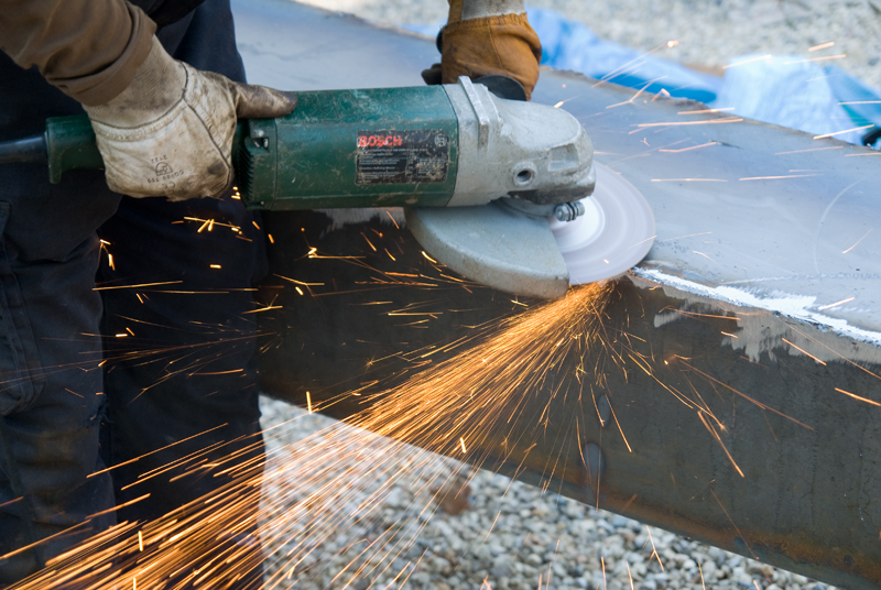 person using electric tool on top of metal surface