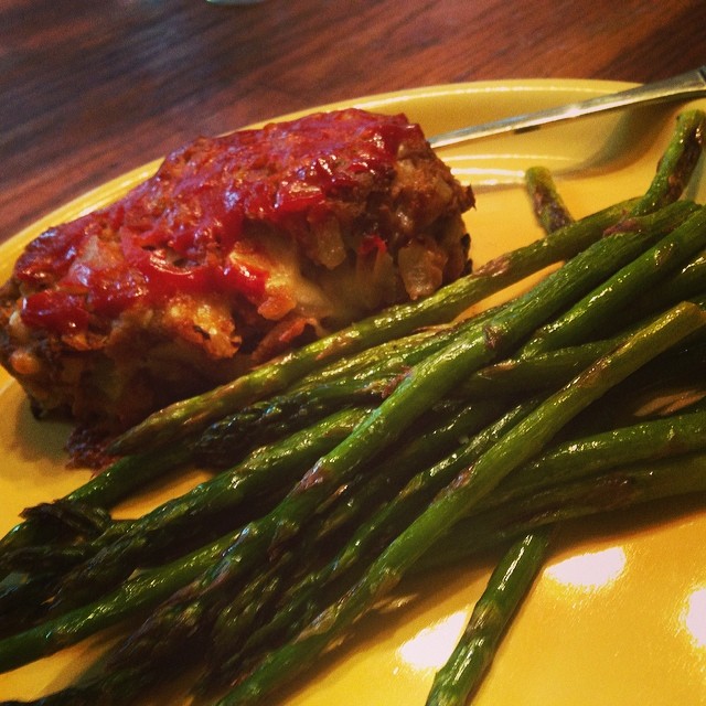 a yellow plate topped with a piece of meat and some asparagus