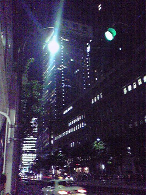 a dark city street filled with lights and a green stop light