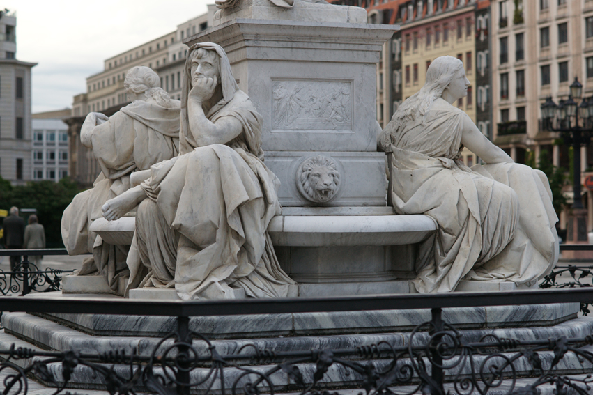 some statues are sitting in front of a fountain