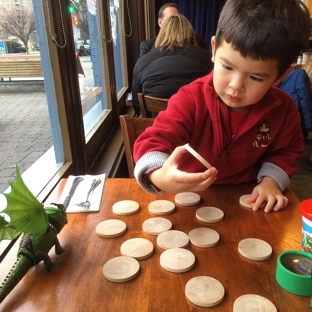 a boy sitting at a table with a board and wooden plates