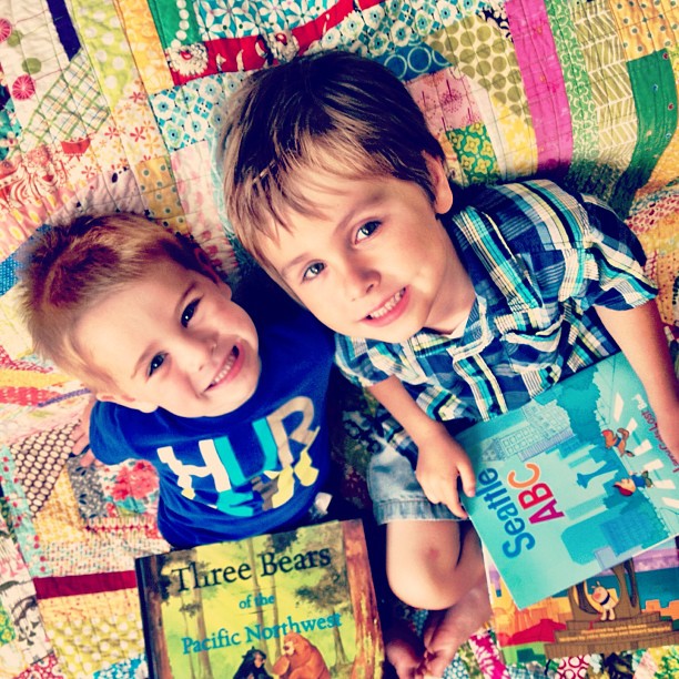 two little boys sitting on top of a quilt