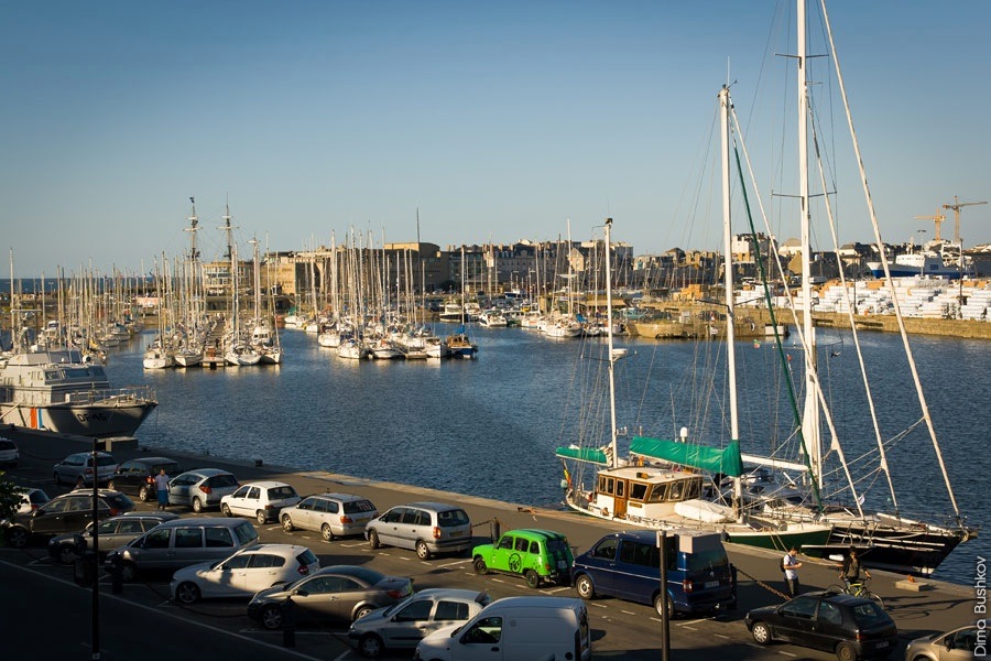 a bunch of cars and boats are parked along the shore