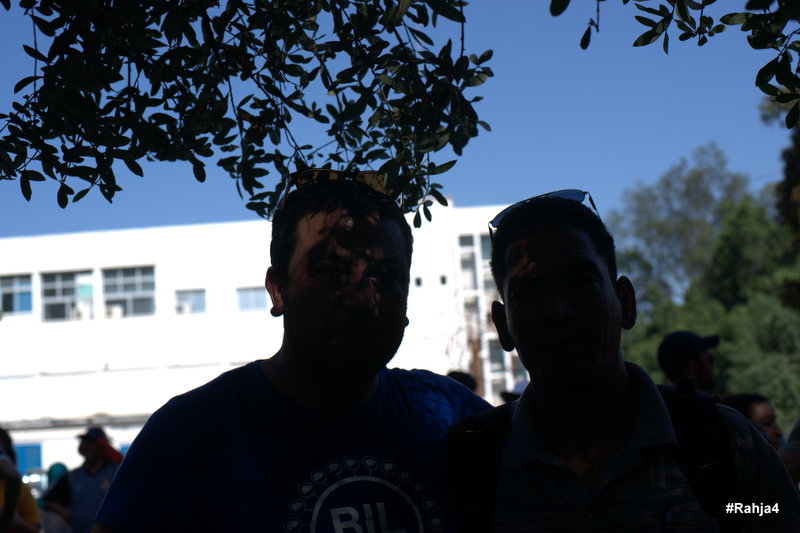 two men covered in mud standing under a tree