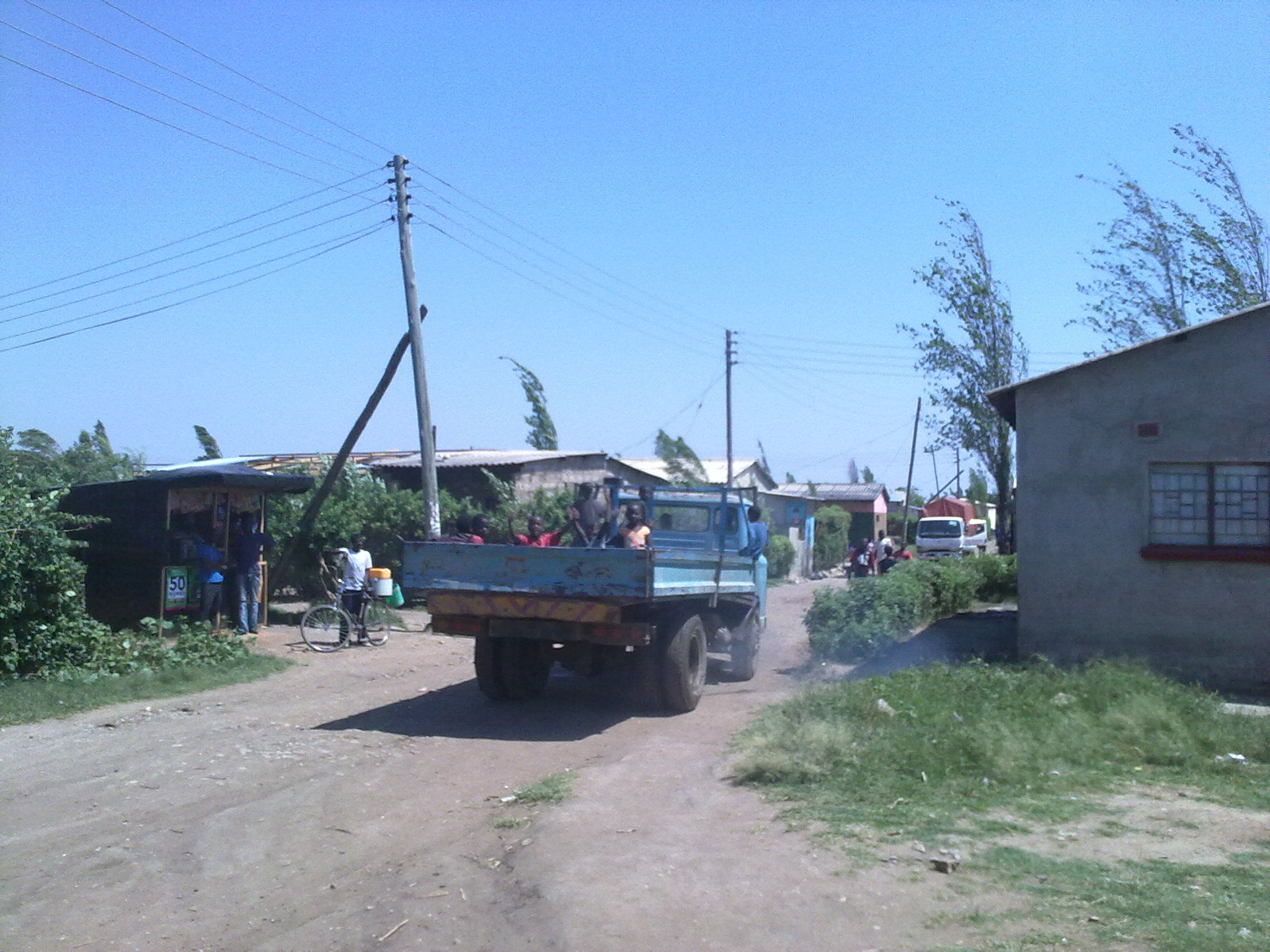 a truck carrying people driving down a rural road