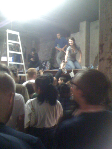 a crowd of people sitting around while a person is standing on top of one