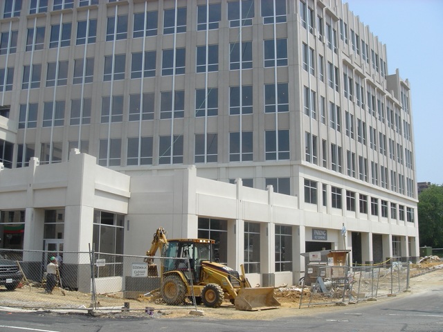 construction equipment sits on a building site in front of an office building