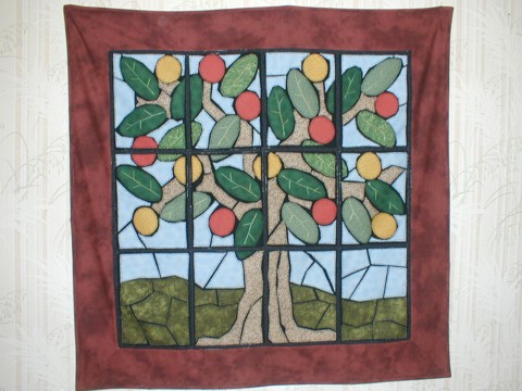 a piece of stained glass with an apple tree