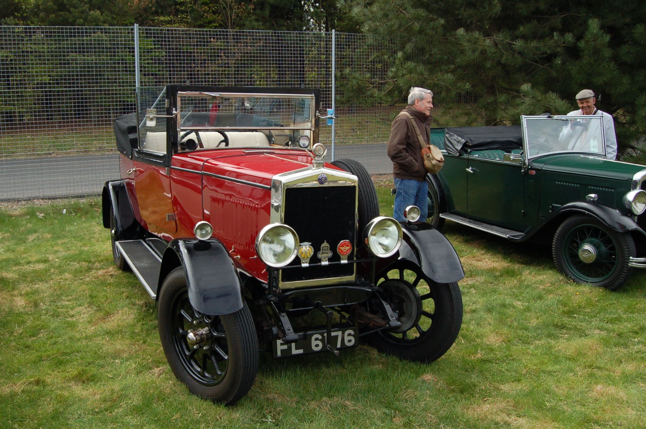 two old fashioned cars parked on a green field