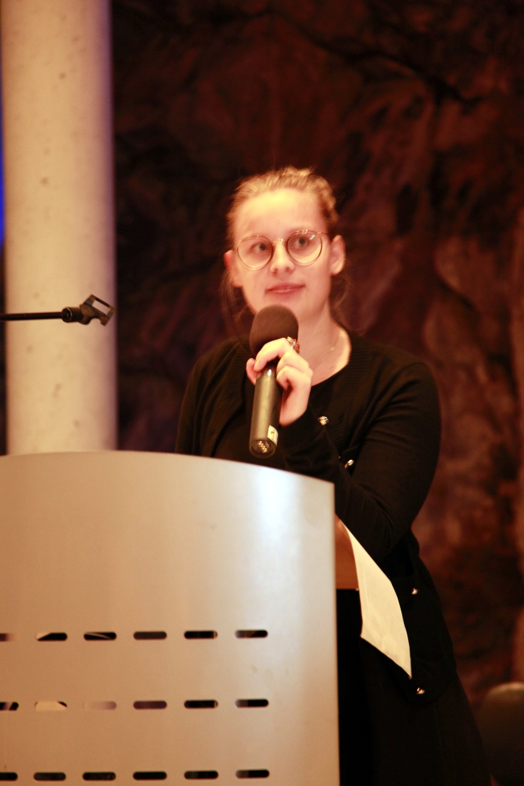 a woman standing in front of a podium holding a microphone