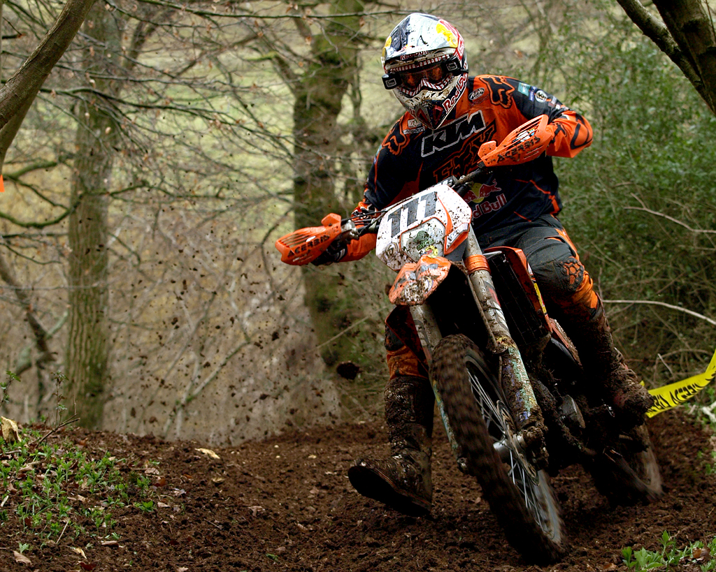 a motorcyclist races on the trail in a muddy area