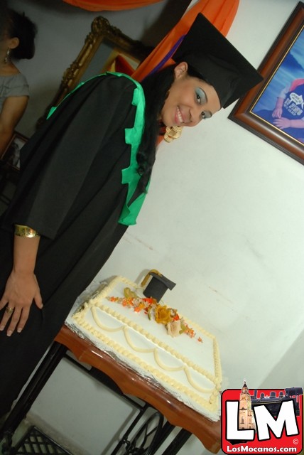 a woman standing behind a sheet cake in graduation regaline