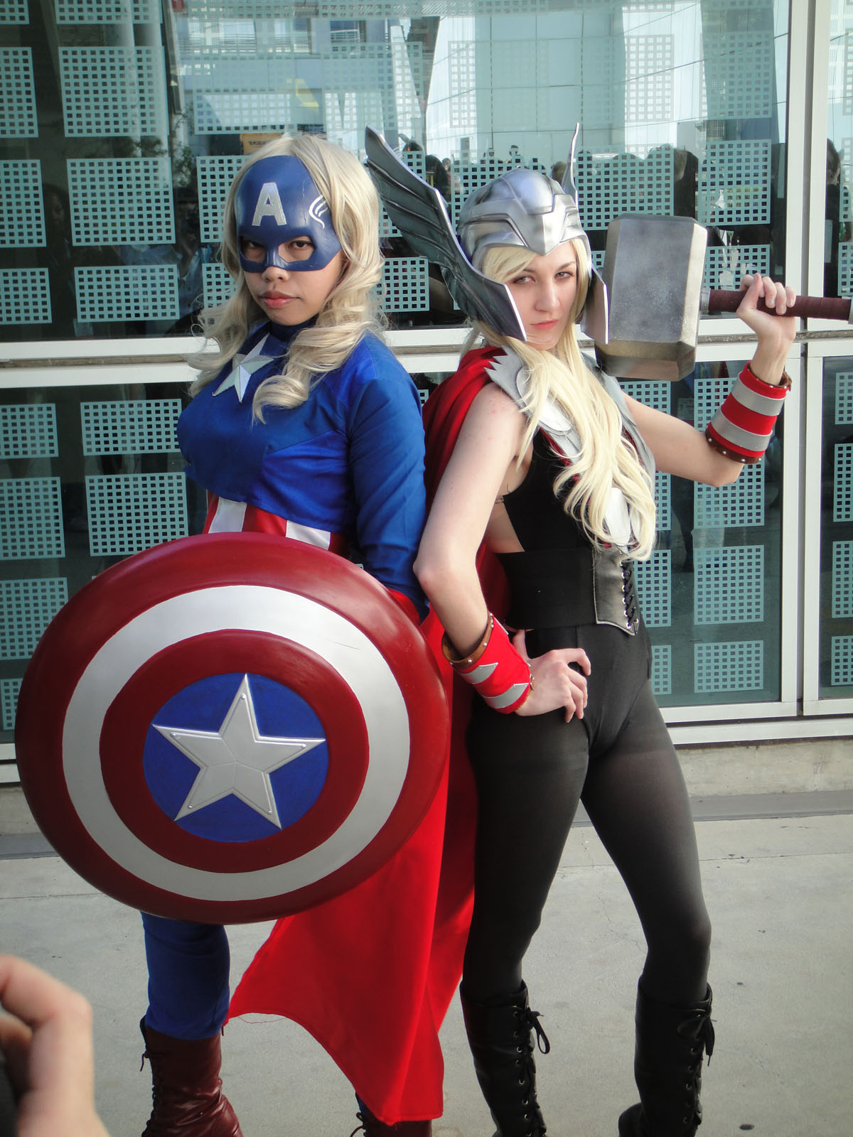 two women in costume holding guns and shield in front of a building