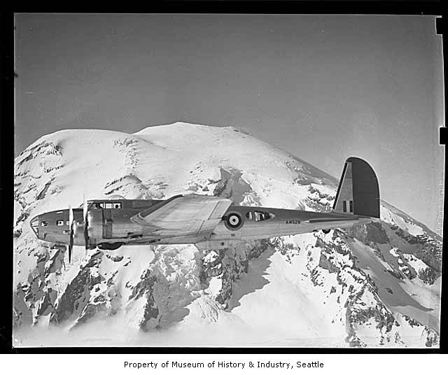 an old time war plane flying over snow covered mountains