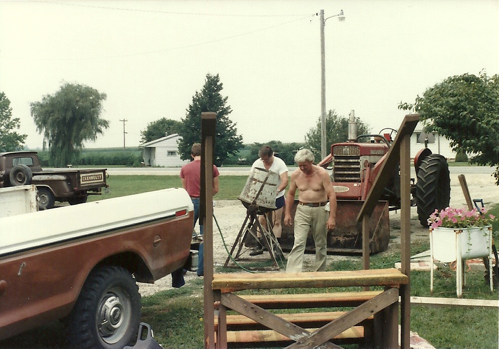 a couple men standing around working on a fence