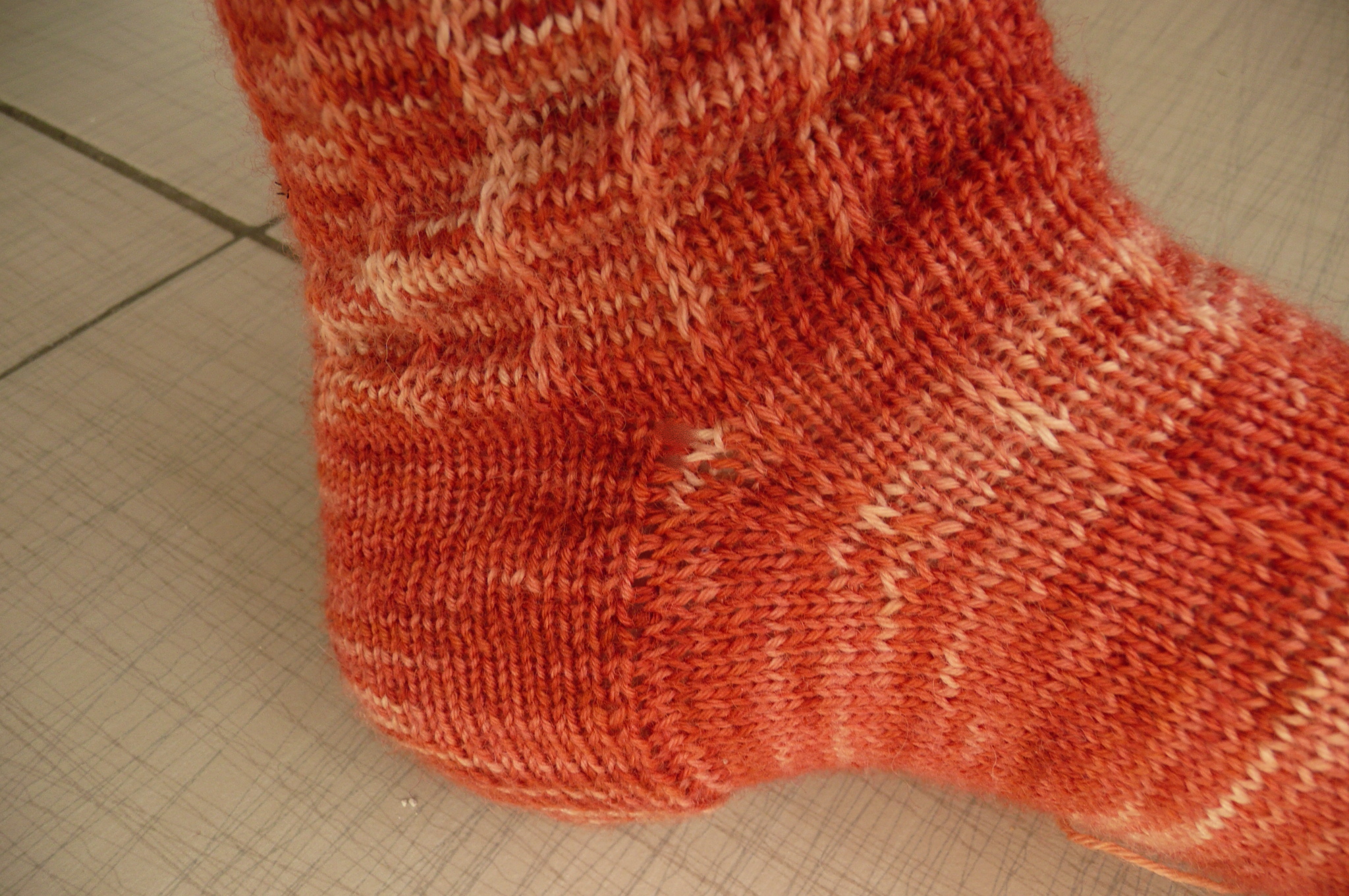 a knitted sock sitting on top of a tile floor