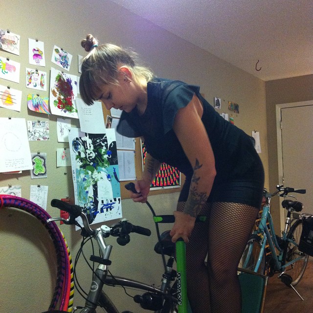 a woman bending over to look at a bike in her room