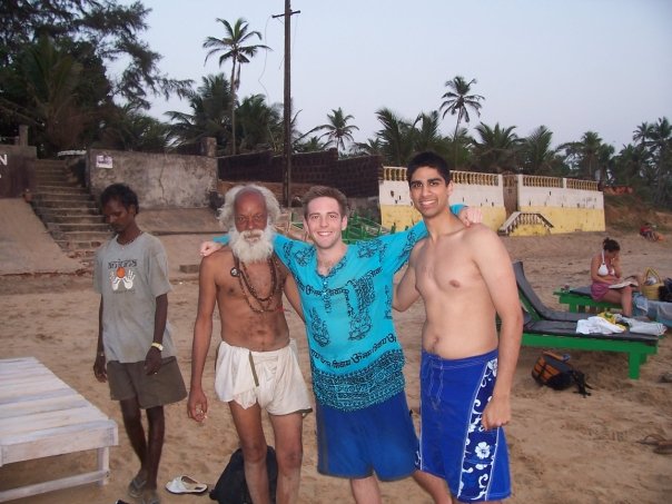 four young men standing together on the beach