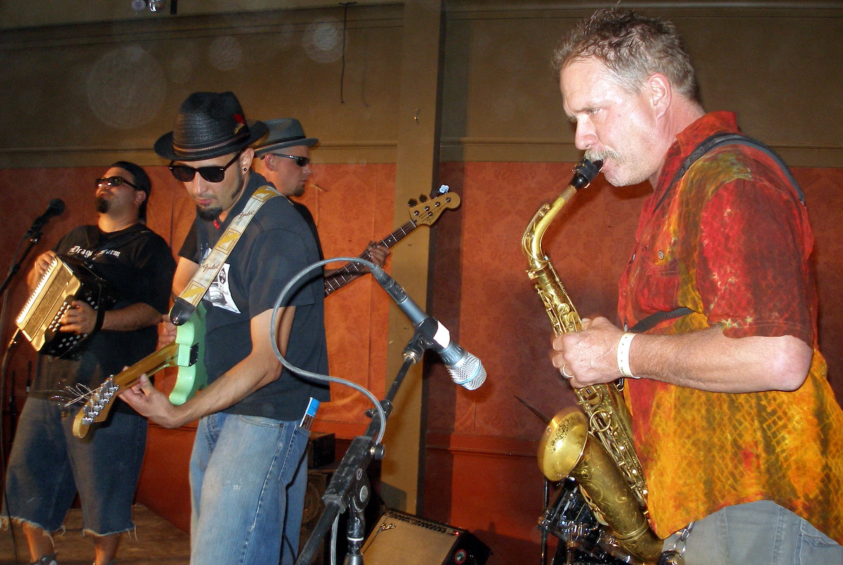 two men are playing saxophone and another man has a guitar in his hand