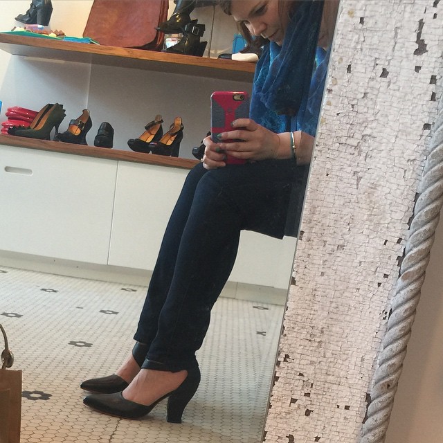 a woman taking a po with her phone in front of a mirror