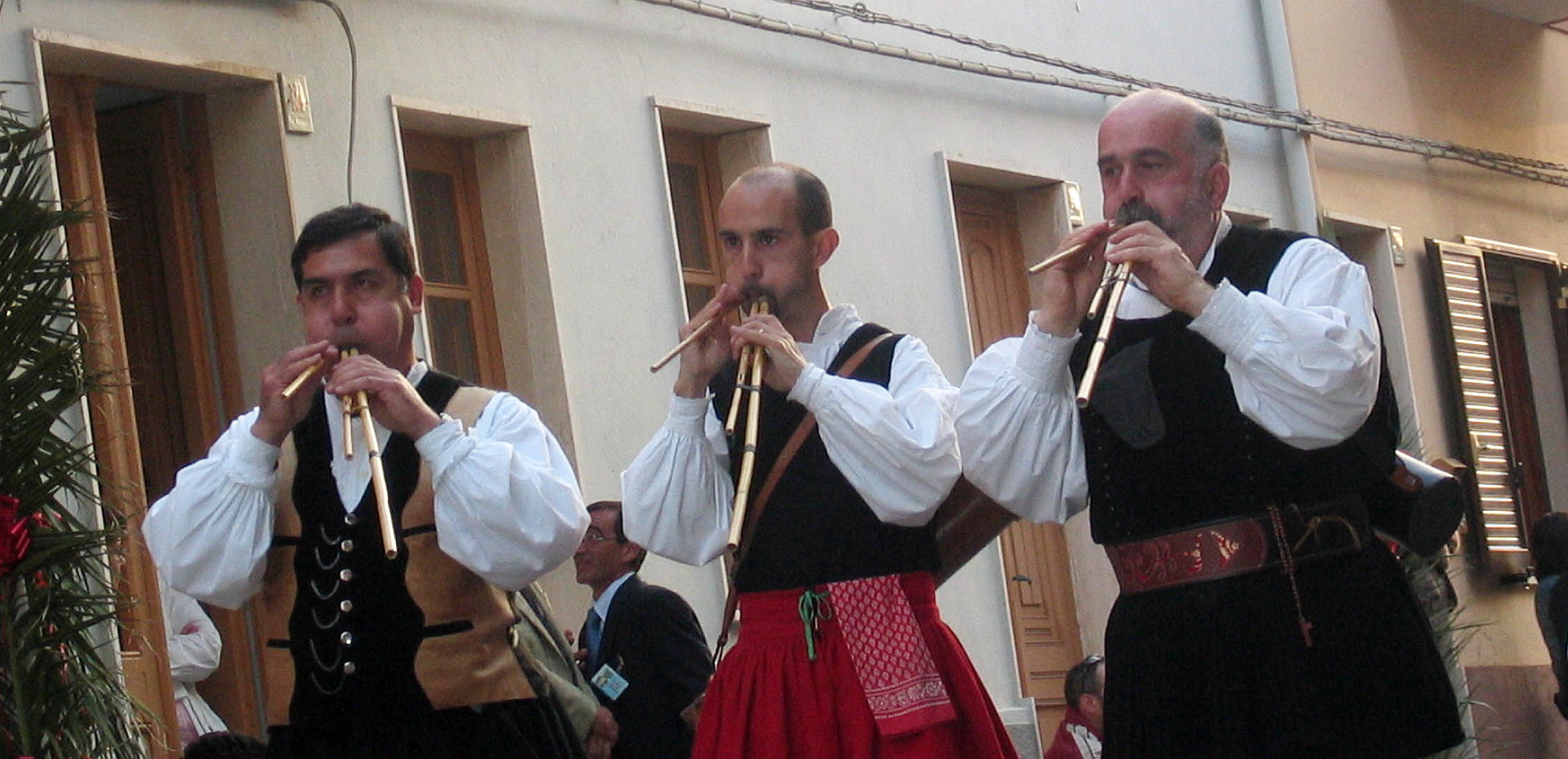 three men dressed in black and white playing instruments