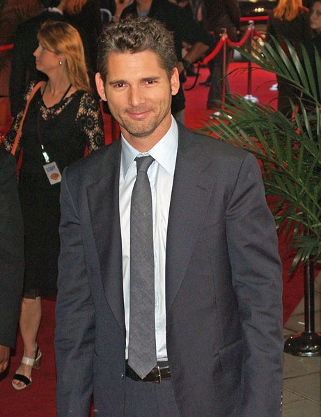 a man in a suit and tie stands on a red carpet