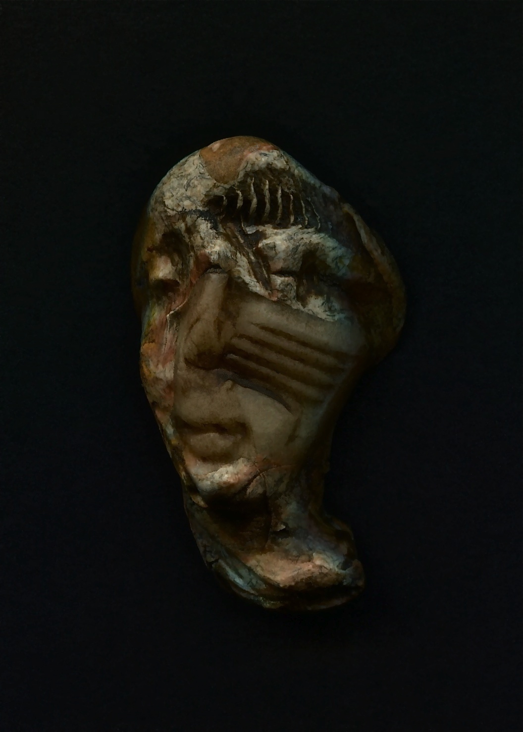 an old silver clay face on display in a dark room