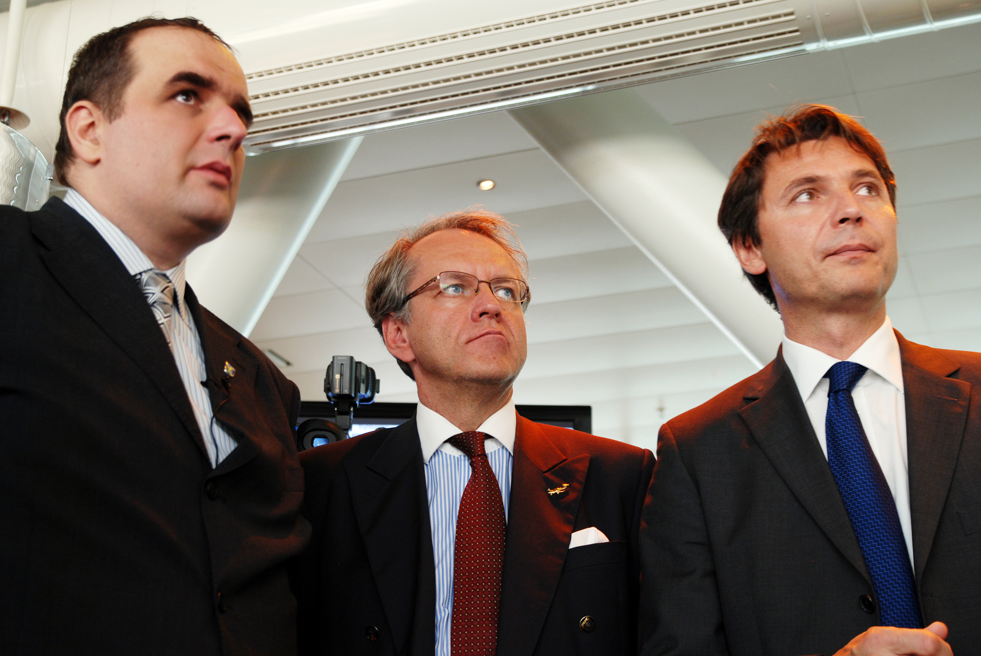 three men in business suits stand next to each other