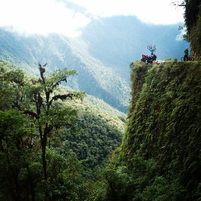 people ride bikes on the side of a cliff